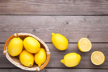 Fresh lemon in basket on gray background. Lemon on brown wooden table