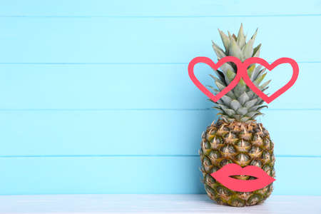 Ripe pineapple with lips and hearts on a blue wooden background with copy spaceの写真素材
