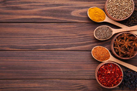 Spices mix on wooden spoons on brown background.の写真素材