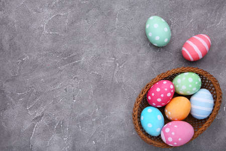 Colorful easter eggs in basket on gray background