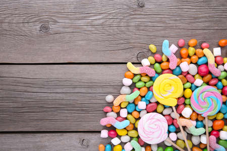 Colorful lollipops and different colored round candy on gray wooden backgroundの写真素材