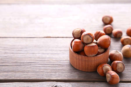 Delicious hazelnut in the wooden bowl on a gray background