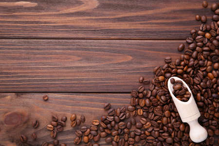 Coffee beans in wood spoon on brown wooden background.の写真素材
