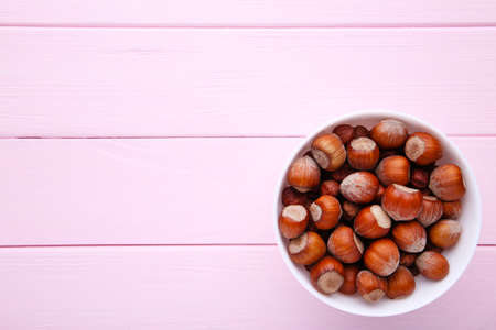 Delicious hazelnut in the bowl on pink wooden backgroundの写真素材