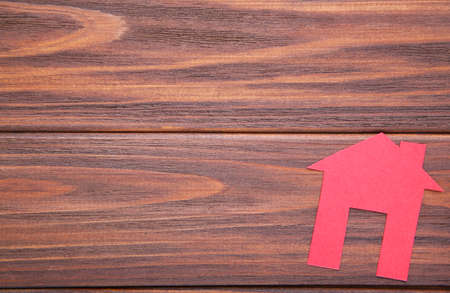 Red paper house on brown wooden background, top viewの写真素材