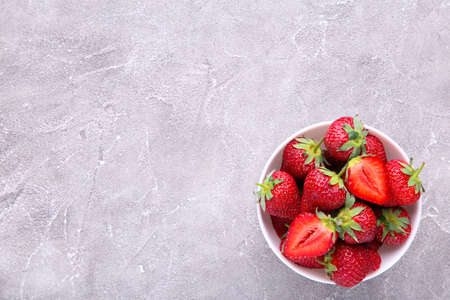 Ripe strawberries in white bawl on gray concrete background, macroの写真素材