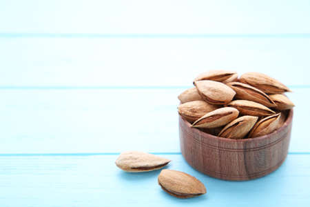 Wooden bowl of almonds on a blue background with copy spaceの写真素材
