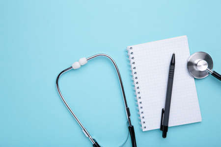 Stethoscope with notebook on blue background. Top viewの写真素材
