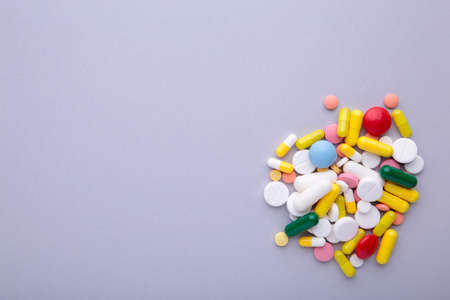 Colored pills and tablets on a gray background with copy spaceの写真素材