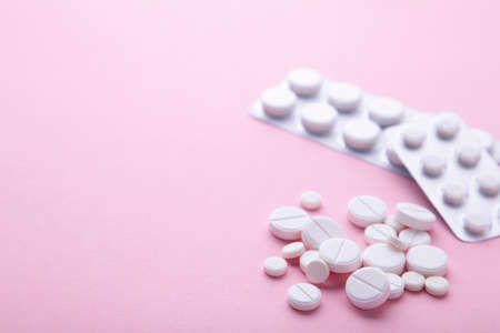 White pills and tablets on a pink background with copy spaceの写真素材