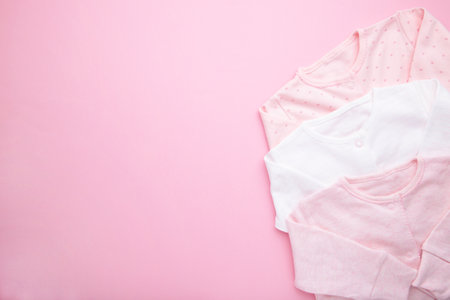Baby clothes for newborn girl on pink backgroundの写真素材