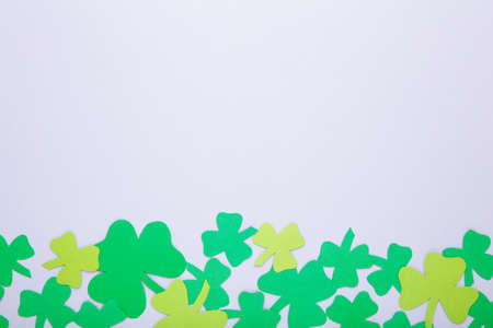 Happy Saint Patrick's of handmade paper clover leaves on gray background with copy space.