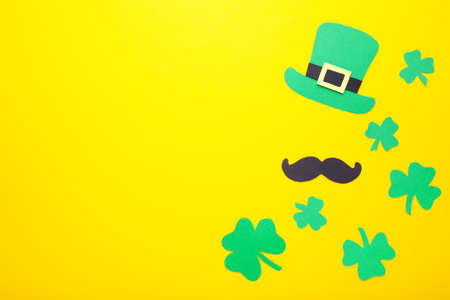 Happy Saint Patrick's of handmade paper clover leaves with coins on yellow background with copy space.の写真素材
