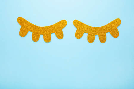 Glitter eyelashes on blue background with copy space. Top view