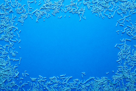 Blue sprinkles on a blue background, top view