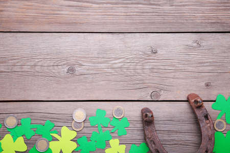 Happy Saint Patrick's of handmade paper clover leaves, horseshoe and coins on gray wooden background with copy space.の写真素材