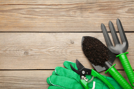Gardening tools with soil on gray wooden background. Spring concept