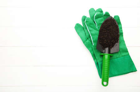 Green garden tools shovel with gloves on white background with copy spaceの写真素材