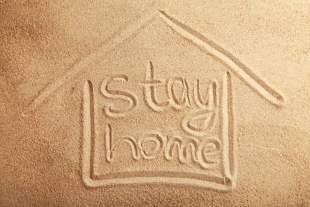 The inscription stay home on the sandy beach. View from aboveの写真素材