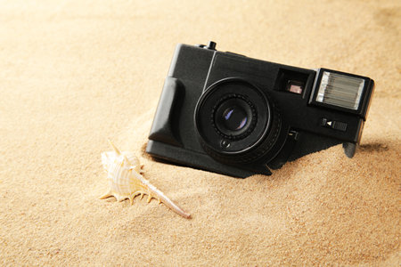 Retro camera in the sand with seashell on a beach. Top viewの写真素材