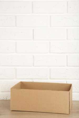 Cardboard box on white brick wall background.