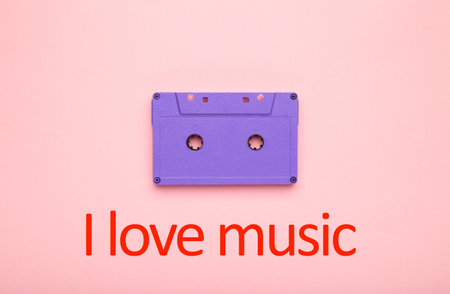 Inscription I love music with old colorful cassette on a pink background. Music day