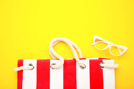 Summer bag with sunglasses on yellow background. Beach accessories, top viewの写真素材