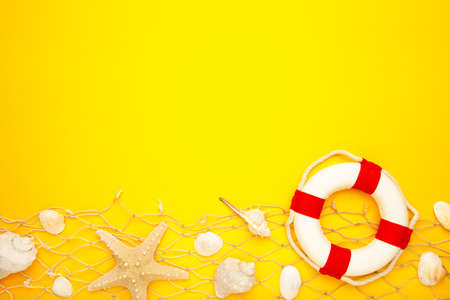 Red-white lifebuoy with sand and seashells on blue background. Top view