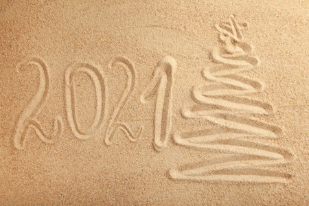 2021 new year text with christmas tree on sand background. Top viewの写真素材