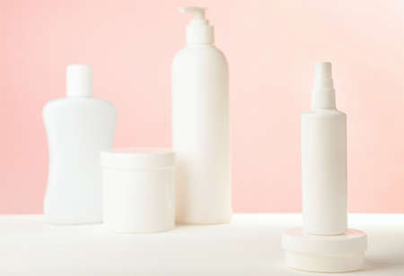 White cosmetic bottles on pink background. Set of bottles