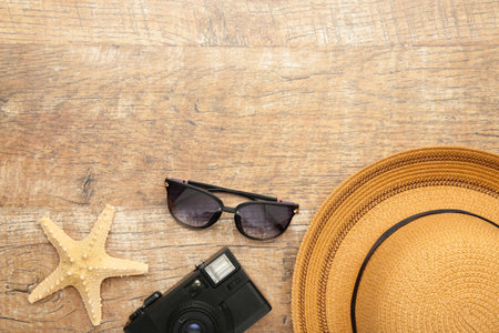 Beach hat with seashells and sand on broun background, flat lay