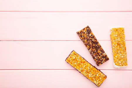 Healthy snack, muesli bars with raisins and dried berries on a pink background with copy space. Top viewの写真素材