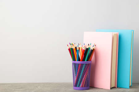 Multi colored school books and pencils on gray background with copy space. Back to school
