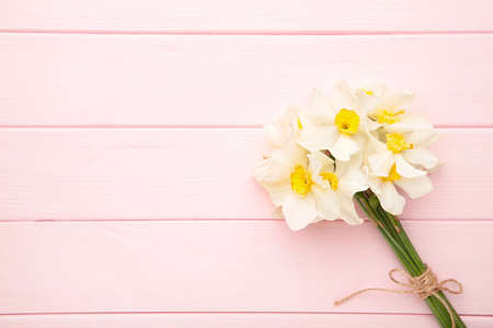 Spring bouquet of narcissus on pink wooden background. Top viewの写真素材