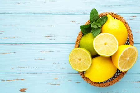 Organic lemons and limes in a basket on blue wooden background. Top viewの写真素材