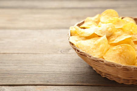 Potato chips in basket on gray wooden background. Top view