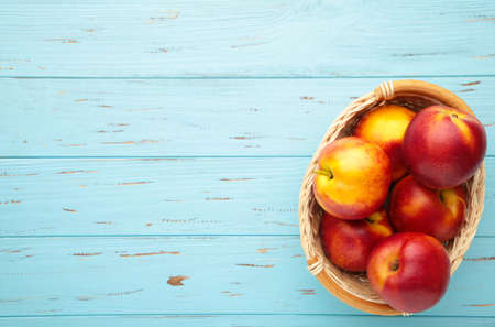 Nectarines in a basket on blue background with copy space. Top viewの写真素材