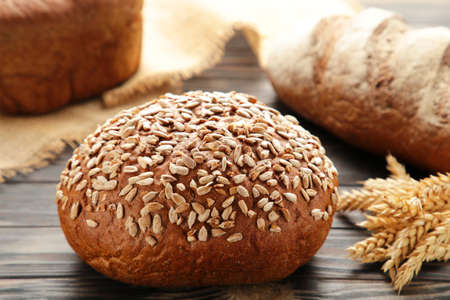 Fresh dark bread with spikelet of wheat on brown wooden table. Top view