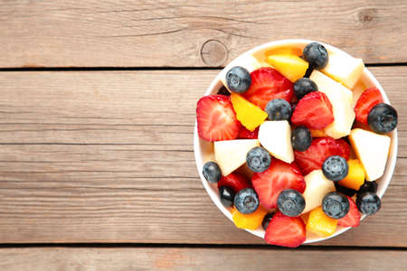 Salad with fresh fruits and berries on gray wooden background with copy space. Top viewの写真素材