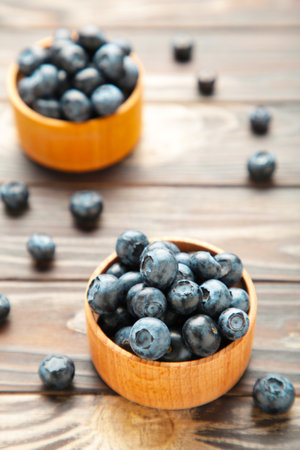 Blueberries in a bowls on brown wooden table. Top viewの写真素材