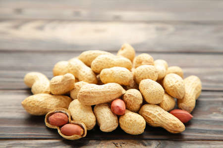 Fried peanuts on a brown wooden background. Top view