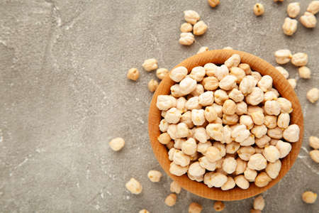 Uncooked dried chickpeas in wooden bowl on gray background. Vegan food concept. Top viewの写真素材