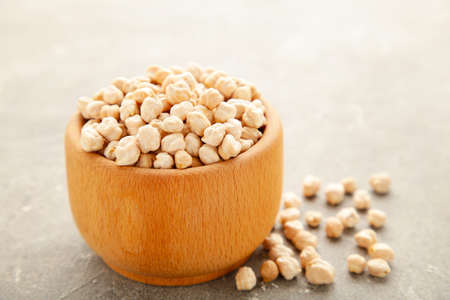 Uncooked dried chickpeas in wooden bowl on gray background. Vegan food concept. Top viewの写真素材