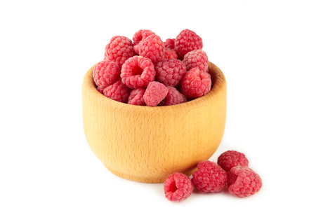 Sweet raspberries in wooden bowl isolated on white background. Top view, high resolution product
