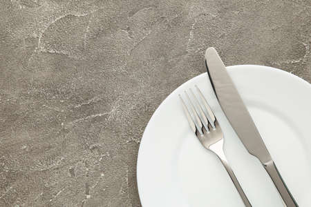 White empty plate with fork and knife on a gray table. Top viewの写真素材