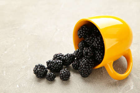 Blackberries in yellow cup on a gray concrete background. Top viewの写真素材