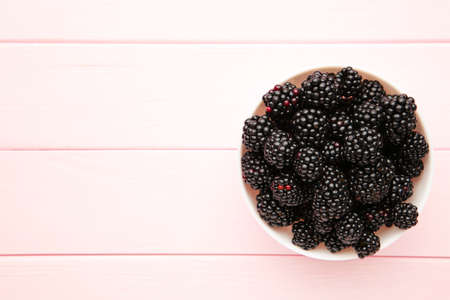 Blackberries in a bowl on pink wooden table. Healthly food