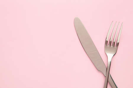 Fork and knife on a pink background. Top viewの写真素材