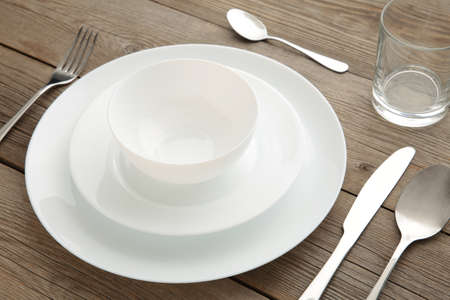 Table setting with white plates, glass, and cutlery - fork, spoon and knife. Shot from above. Copy...