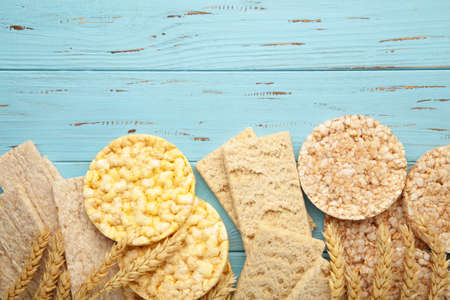 Various types of healthy whole grain crispbreads on blue wooden background. Top view